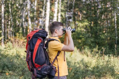 Yürüyüşçü adam dürbünle bakıyor. Manzaranın tadını çıkarıyor.