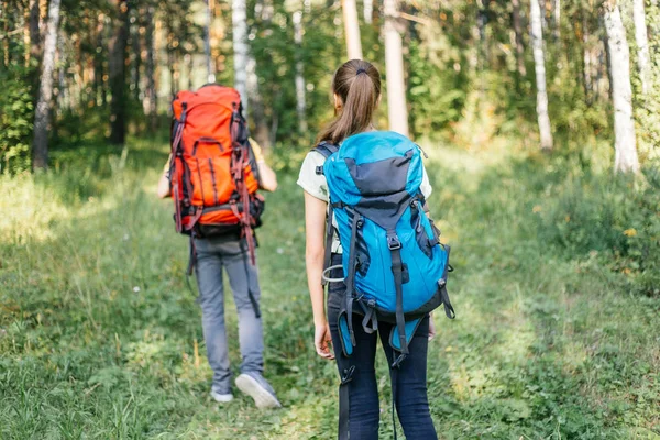 Couple of tourists with backpacks hiking in a forest — Stock Photo, Image