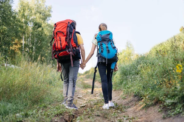 Couple of tourists with backpacks hiking in a forest — Stock Photo, Image