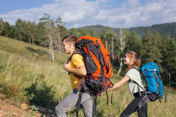 Couple of tourists with backpacks hiking up a mountain — Stock Photo, Image