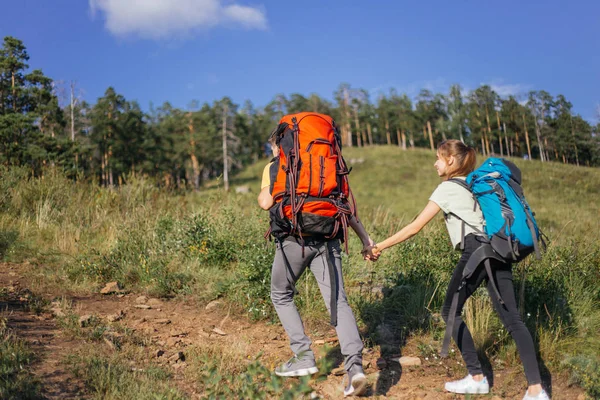 Un par de turistas con mochilas subiendo una montaña —  Fotos de Stock