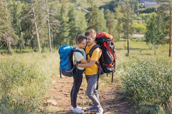 Casal de turistas com mochilas caminhando até uma montanha — Fotografia de Stock