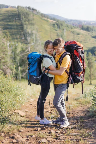 Casal de turistas com mochilas caminhando até uma montanha — Fotografia de Stock