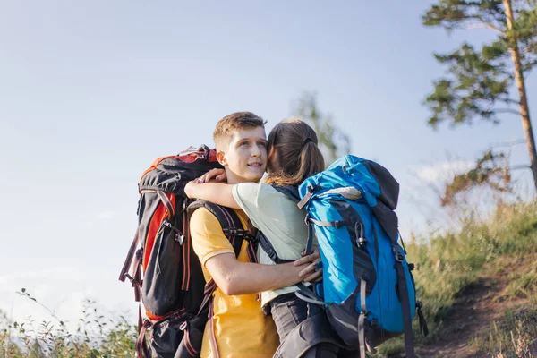 Casal de turistas com mochilas caminhando até uma montanha — Fotografia de Stock