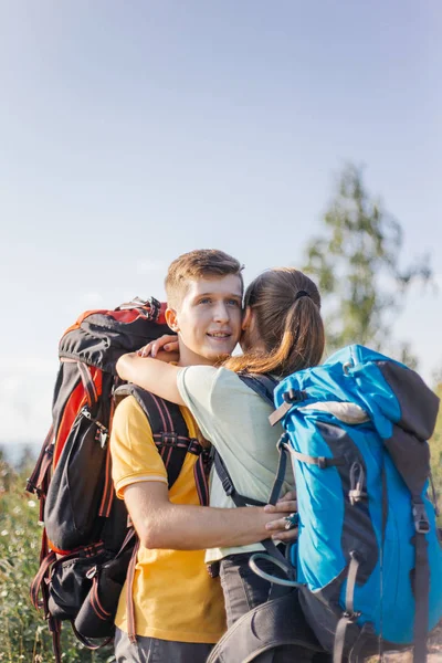 Couple of tourists with backpacks hiking up a mountain — Stock Photo, Image