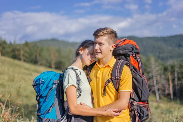 Couple of tourists with backpacks hiking up a mountain — Stock Photo, Image