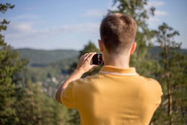Uzun yürüyüşe çıkan kimse bir dağ bir cep telefonu ile fotoğraf çekme