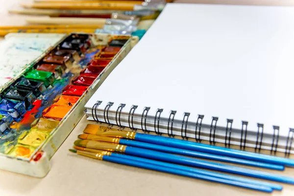 Work space on a table with pencils and paintbrushes — Stock Photo, Image