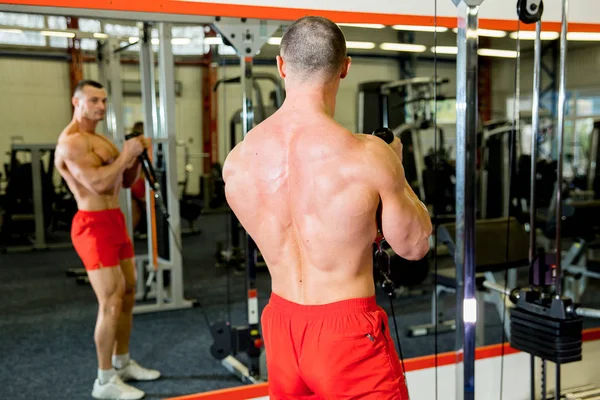 Fisiculturista masculino fazendo exercícios em um ginásio — Fotografia de Stock