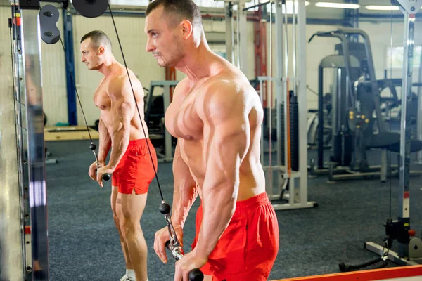 Fisiculturista masculino fazendo exercícios em um ginásio — Fotografia de Stock