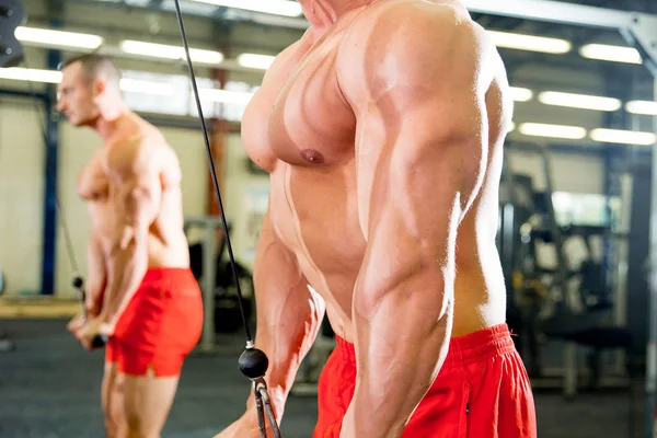 Manliga kroppsbyggare gör övningar i gym — Stockfoto
