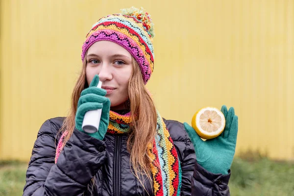 Sick woman with flu is holding a lemon outside