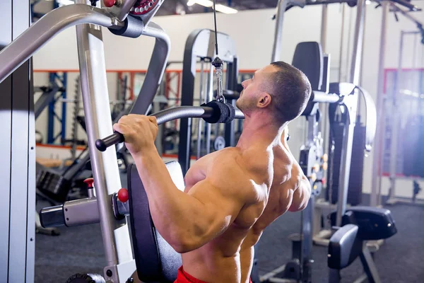 Fisiculturista masculino fazendo exercícios em um ginásio — Fotografia de Stock