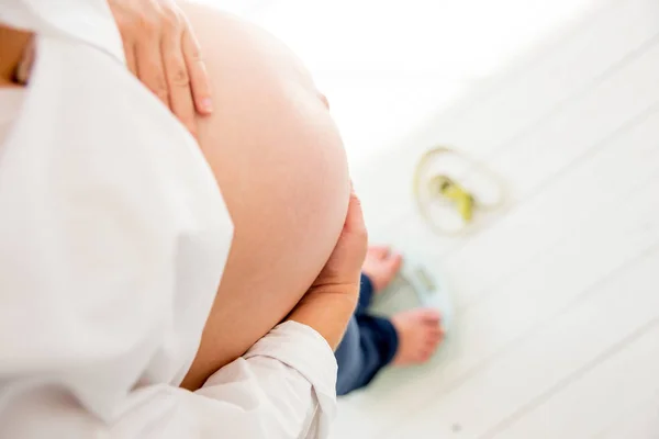 Gravid kvinna stående på skalor att styra viktökning — Stockfoto