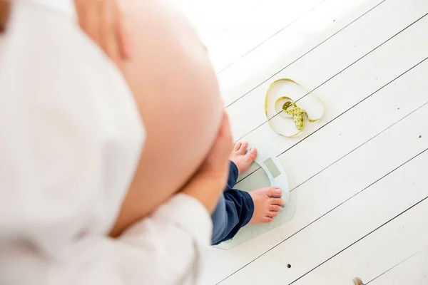 Gravid kvinna stående på skalor att styra viktökning — Stockfoto