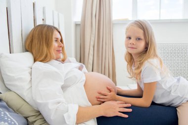 mutlu gülümseyen hamile anne kızıyla birlikte evde sarılma