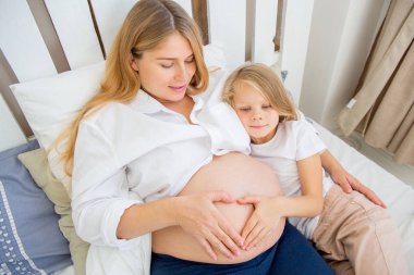 mutlu gülümseyen hamile anne kızıyla birlikte evde sarılma