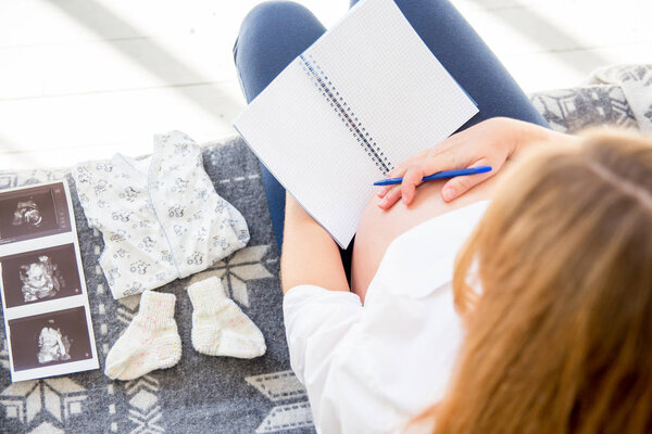 happy pregnant woman choosing baby clothes for her baby