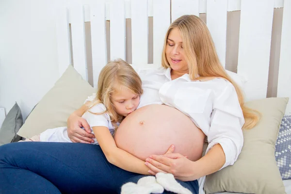 Heureux souriant mère enceinte étreignant avec sa fille à la maison — Photo