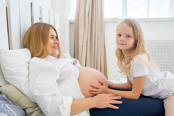 Glada leende gravid mamma kramas med sin dotter hemma — Stockfoto