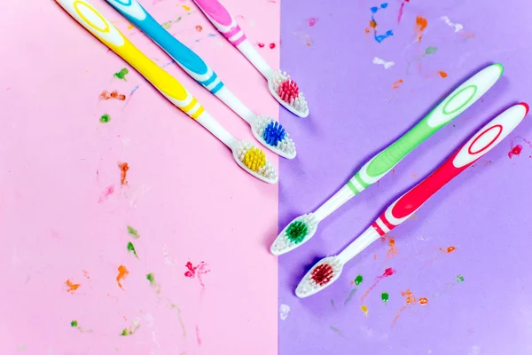 Escovas de dentes e uma pasta de dentes em um fundo colorido — Fotografia de Stock