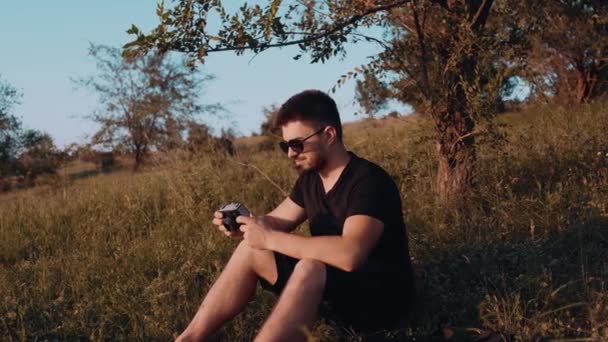 Primer plano de las manos del fotógrafo masculino maduro sosteniendo la cámara con la vieja película. Preparar los ajustes y, finalmente, tomar fotos al atardecer — Vídeo de stock