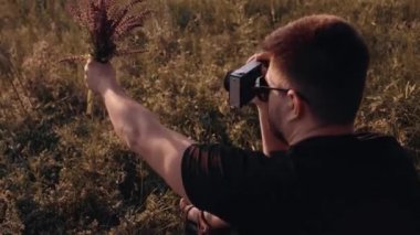 Doğaya aşık karizmatik bir adam mor bir çiçek buketinin fotoğraflarını çeker. Yukarıdan aşağıya çekilen video.
