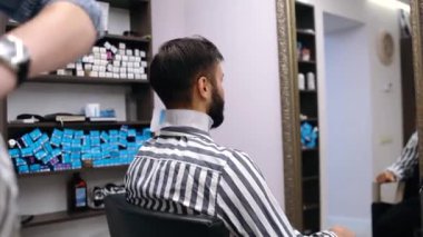 Profesyonel berber müşteriyi saç kesimine hazırlar. Modern küçük işletme konsepti. Yeni Covid-19 virüsü nedeniyle fabrikaların yasaklama döneminden sonra yeniden açılması.