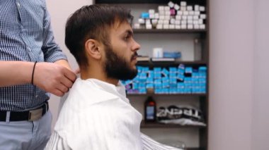 Berber müşteriyi saç kesimi için hazırlar, peçete bağlar. Modern küçük işletme konsepti