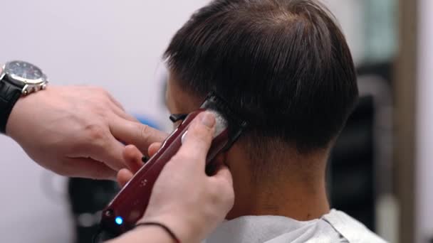 Перукар робить зачіски для клієнтів в перукарні, використовуючи зачіску для волосся, чоловічі зачіски, перукарню та салон гоління — стокове відео