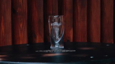 Bir bar ağının garsonu taze birayı açar ve özel bir bardağa döker.