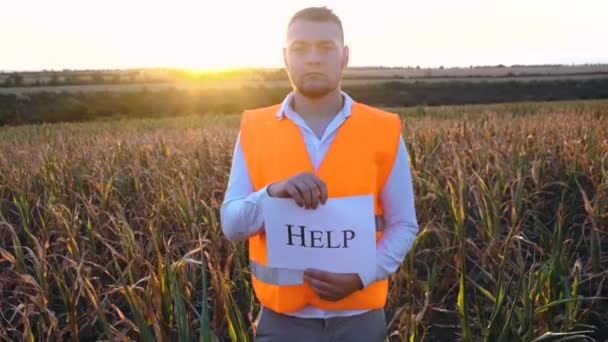 Porträtt av en ledsen ung bonde som håller en plakett med inskriptionen Hjälp. — Stockvideo