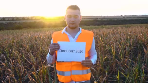 Portrét smutného mladého farmáře držícího plaketu s nápisem Sucho 2020. — Stock video