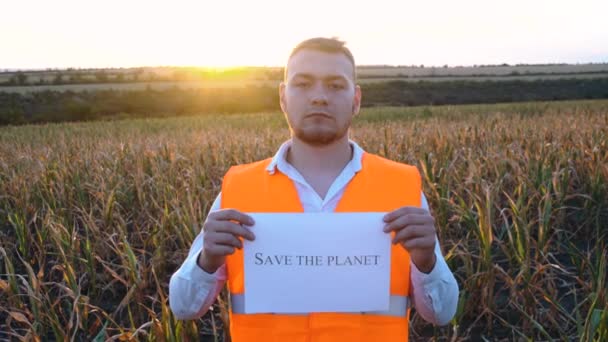 Retrato de un joven agrónomo triste sosteniendo una placa con la inscripción Save this Earth. — Vídeo de stock