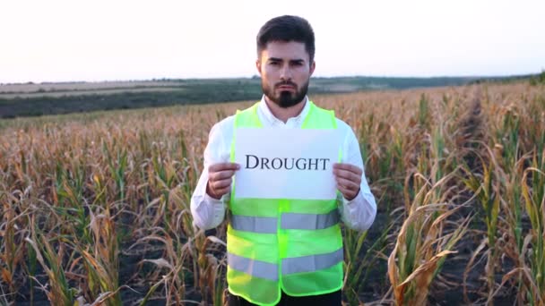 Porträtt av en ung deprimerad bonde med ett plakat i handen med budskapet DROUGHT — Stockvideo