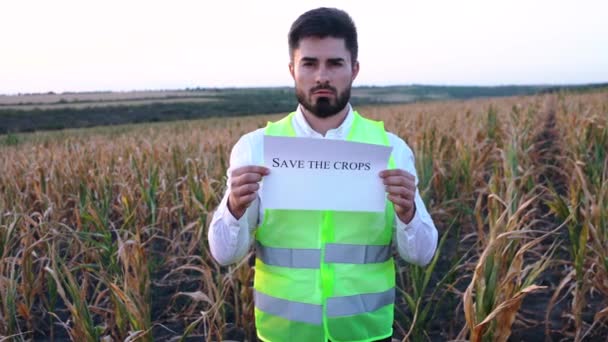 Porträttet av en deprimerad ung bonde som håller ett plakat i handen med budskapet SAVE THESE CROPS. — Stockvideo
