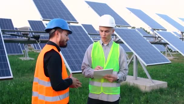 Un ingeniero senior con un plan de instalación de paneles solares explica a un trabajador cómo hacerlo — Vídeos de Stock