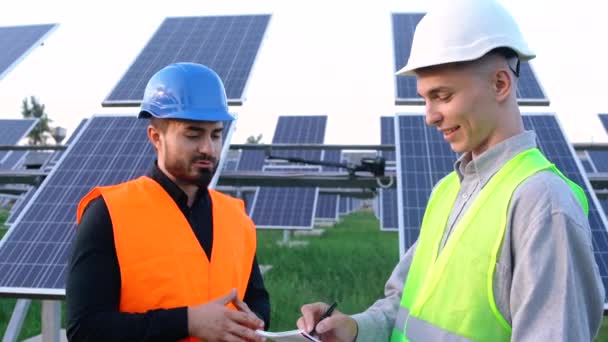 O retrato de dois engenheiros com o plano de projeto na fazenda solar. — Vídeo de Stock