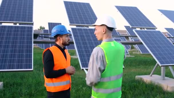 Två ingenjörer i särskild uniform diskuterar installationen av solig batteriel. — Stockvideo