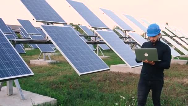 Kavkazský průmyslový inženýr v uniformě procházející se mezi solárními panely ke zkoumání. — Stock video