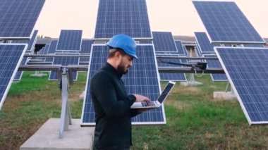 Olgun Kafkas mühendisi güneş paneli pillerini kontrol etmek için dizüstü bilgisayar kullanıyor.