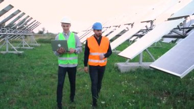 Güneş panelleri alanında yürüyen iki teknisyen.