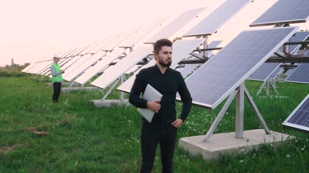 Портрет кавказского промышленного рабочего, стоящего на экологическом поле солнечных панелей. — стоковое видео