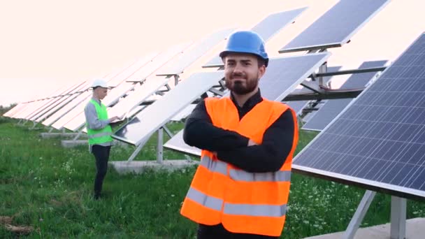 Young smiling engineer looks at the camera near the construction. — Stock Video