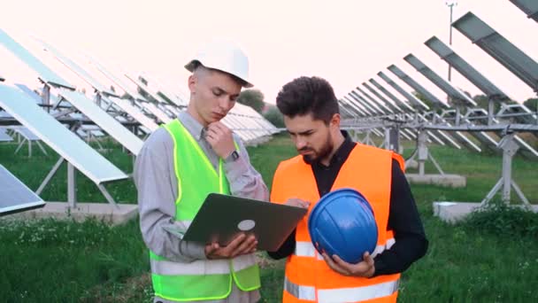 Portrét dvou charismatických inženýrů, kteří se učí o stavebním plánu solární panelové stanice. — Stock video