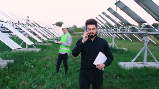 En los ingenieros solares, con el portátil en la granja solar, en un unifor especial. — Vídeos de Stock