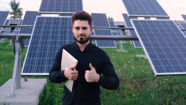 Retrato de trabalhador de ecologia caucasiana com chapéu duro em pé no campo com painéis solaer. Trabalhadores industriais. — Vídeo de Stock