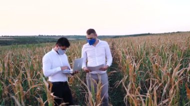 İki tarım uzmanı mısır tarlasında yeni bir sulama sistemini tartışıyor..