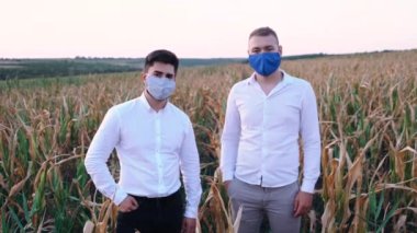 Kuraklıktan ciddi şekilde etkilenen mısır tarlasında koruyucu maskeler takan iki hayal kırıklığına uğramış çiftçinin portresi..