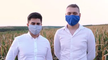 Kuraklıktan ciddi şekilde etkilenen mısır tarlasında koruyucu maskeler takan iki hayal kırıklığına uğramış çiftçinin portresi..